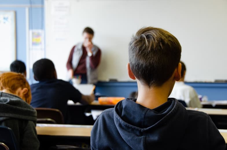 A student in a classroom during a lesson, viewed from behind
